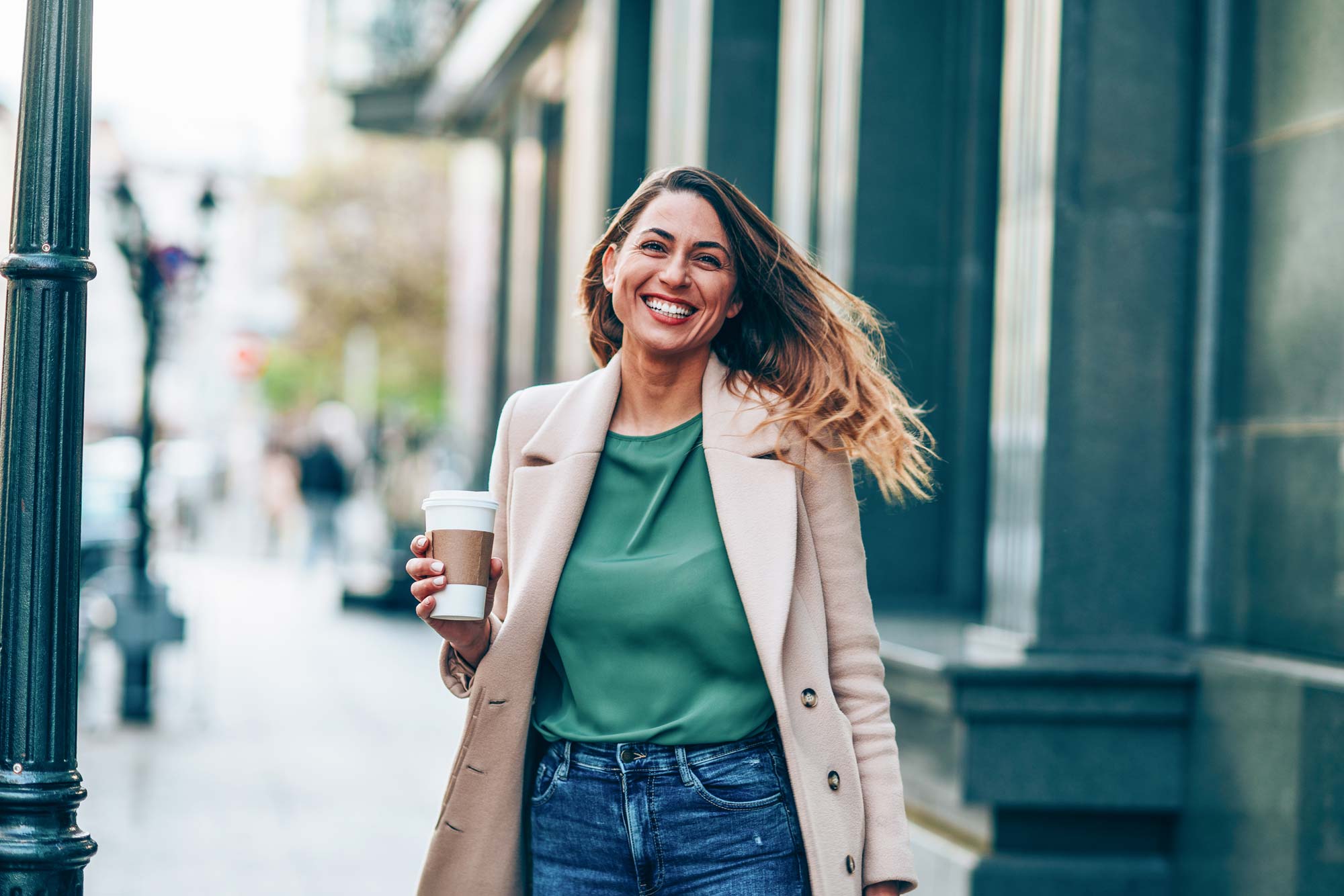 En kvinna ser väldigt glad ut och håller i en kaffemug.